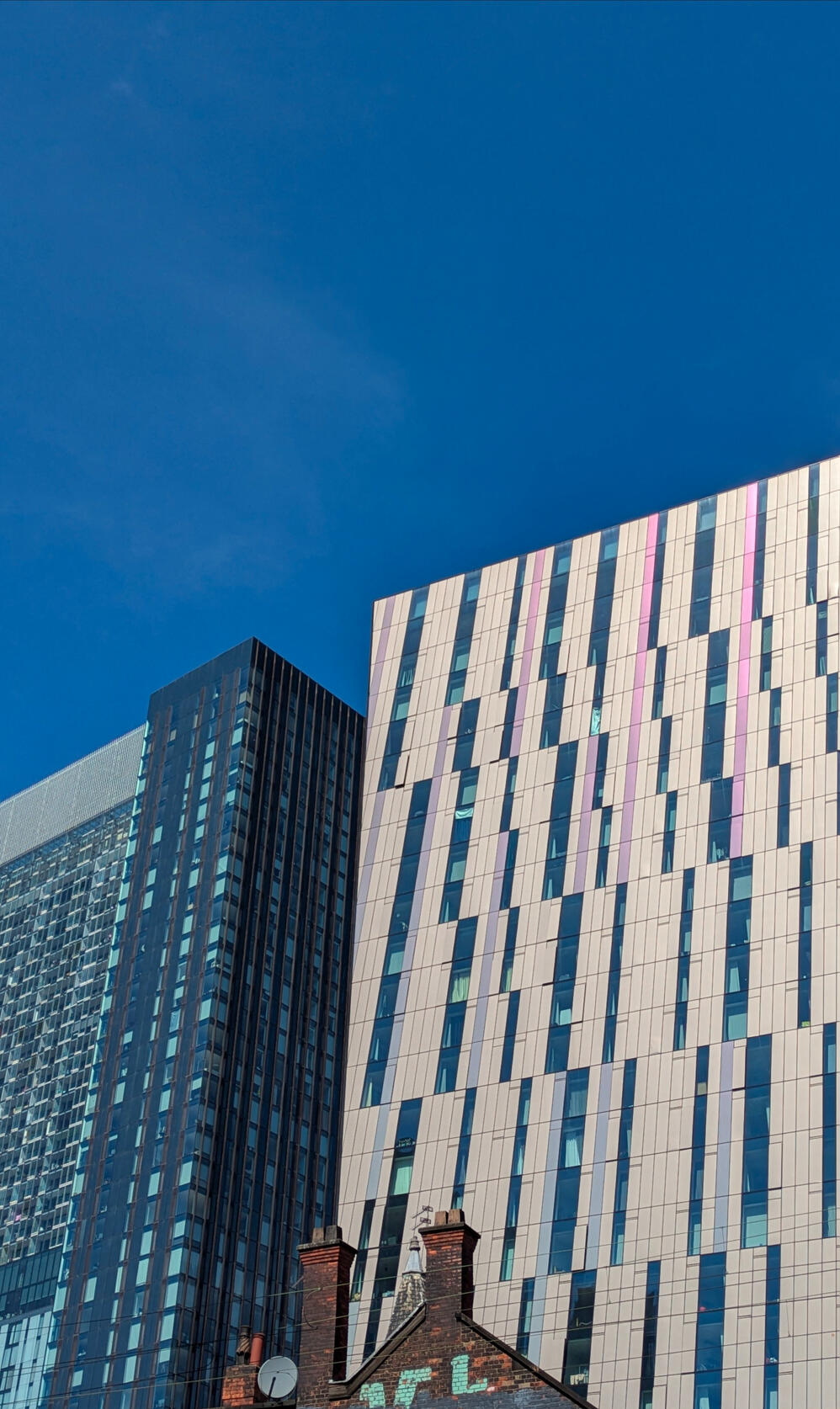 Blue sky contrasting against modern high rise contrasting against old, red brick, Bingley